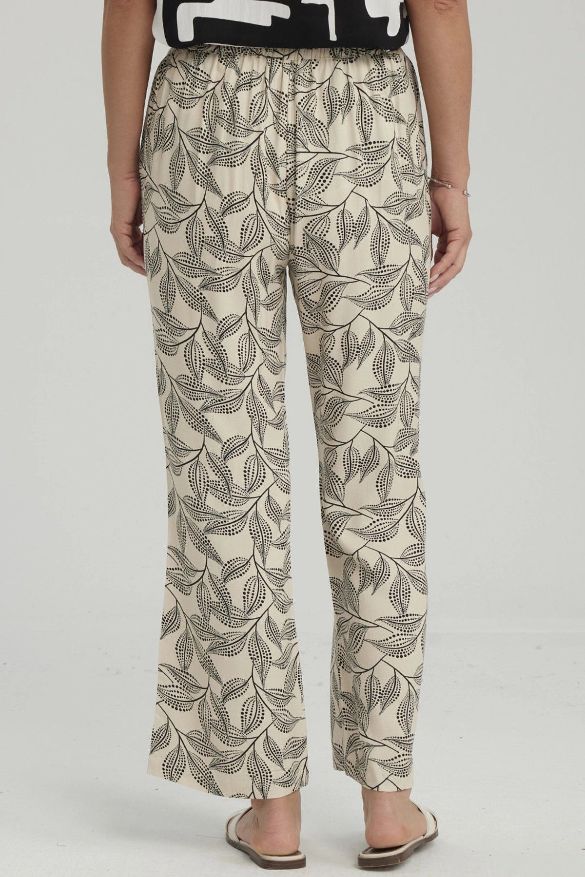 Pantalón pescador beige con estampado de hojas negras grandes estilo gráfico ocupando toda la prenda