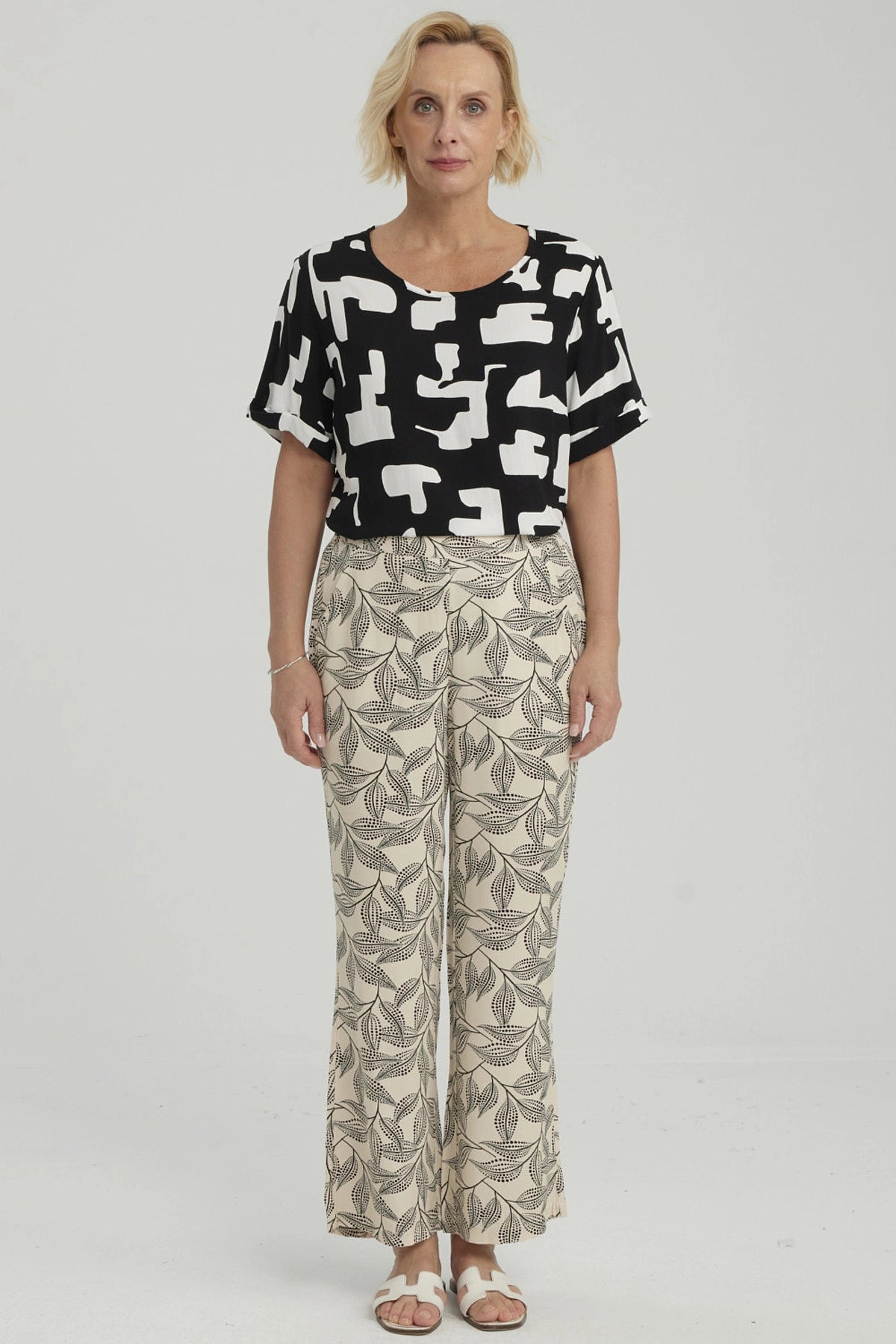 Pantalón pescador beige con estampado de hojas negras grandes estilo gráfico ocupando toda la prenda