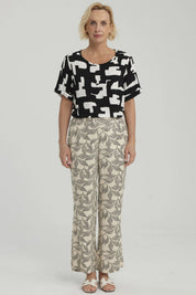 Pantalón pescador beige con estampado de hojas negras grandes estilo gráfico ocupando toda la prenda