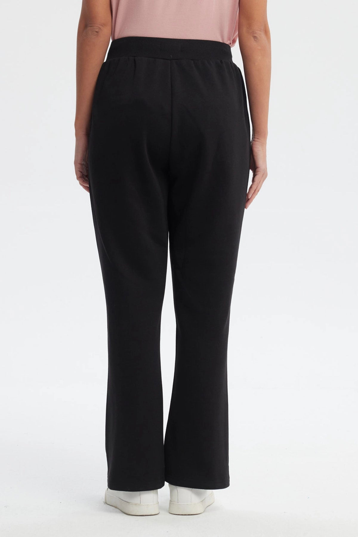Pantalón buzo flare negro para mujer con cintura elástica y detalle de ojales metálicos en los bolsillos prenda lisa