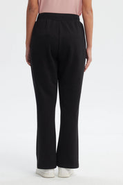 Pantalón buzo flare negro para mujer con cintura elástica y detalle de ojales metálicos en los bolsillos prenda lisa
