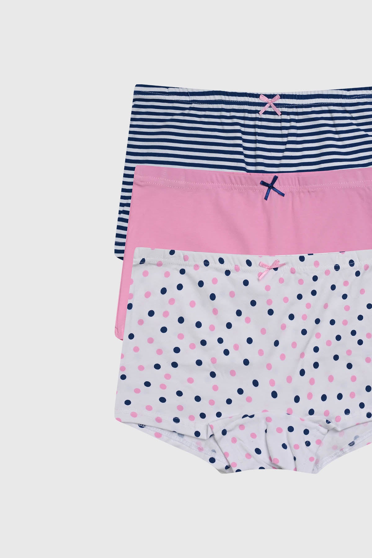 Calzón niña tipo short corto rosado con diseño liso y detalles de lazo azul pequeño en la parte superior frontal