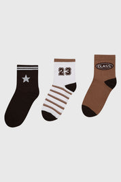 Tripack de calcetines para niña en tonos café con diseños variados incluyendo estrella número 23 y texto Class en la parte superior