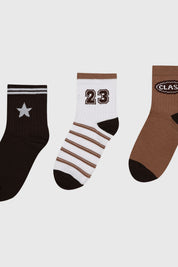 Tripack de calcetines para niña en tonos café con diseños variados incluyendo estrella número 23 y texto Class en la parte superior
