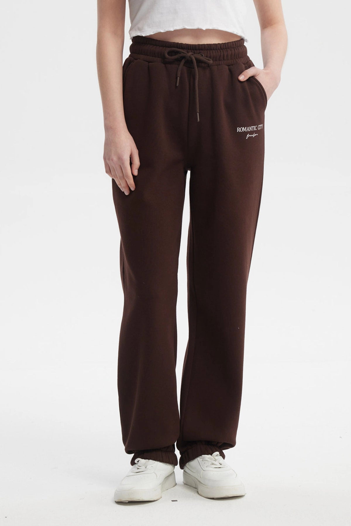 Pantalón jogger café con cintura ajustable y texto 'ROMANTIC CITY' en blanco en la parte superior izquierda