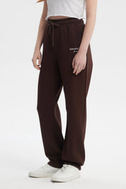 Pantalón jogger café con cintura ajustable y texto 'ROMANTIC CITY' en blanco en la parte superior izquierda