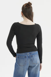Polera negra de mujer con cuello bote y mangas largas sin estampado visible