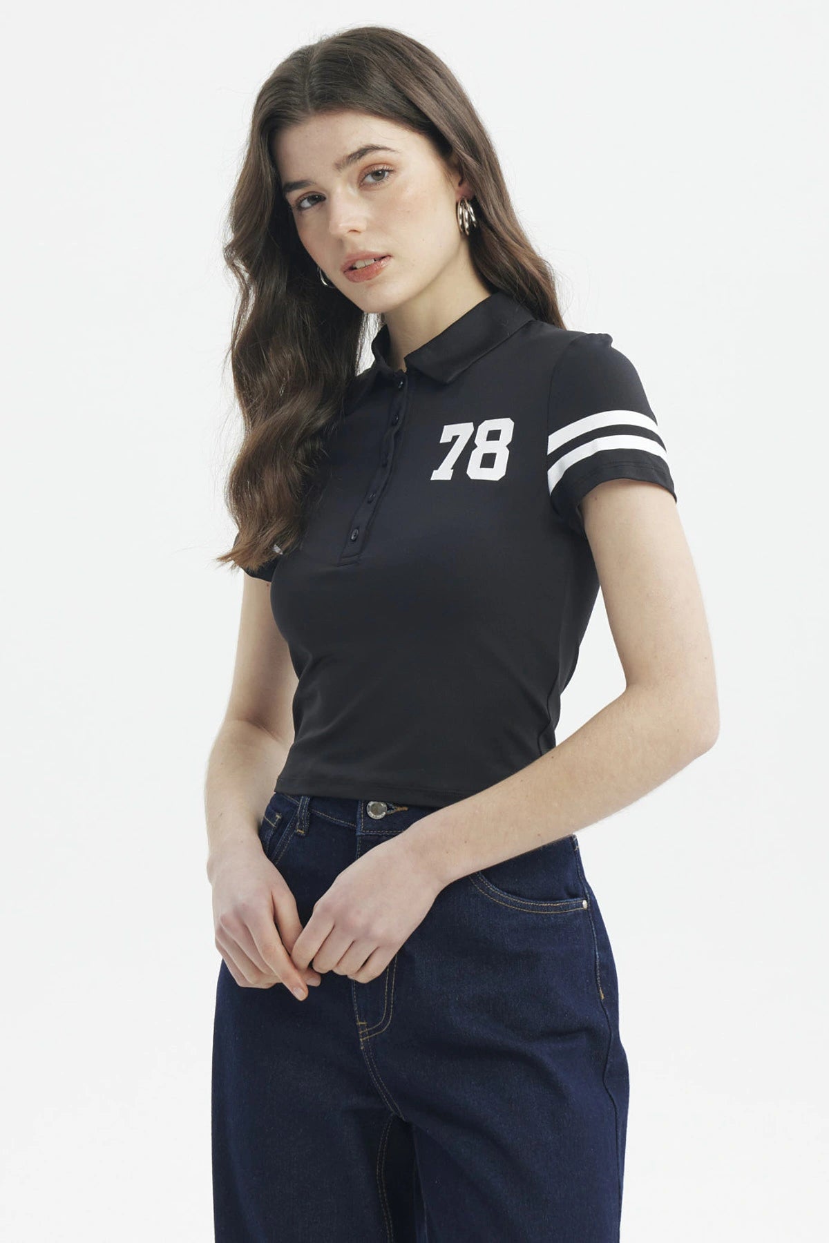Polera negra de mujer con cuello polo y botones estampada con número 78 en el pecho y líneas blancas en mangas