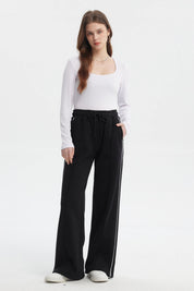 Pantalón buzo negro de mujer tipo wide leg con líneas blancas laterales y cintura elástica sin estampa lisa