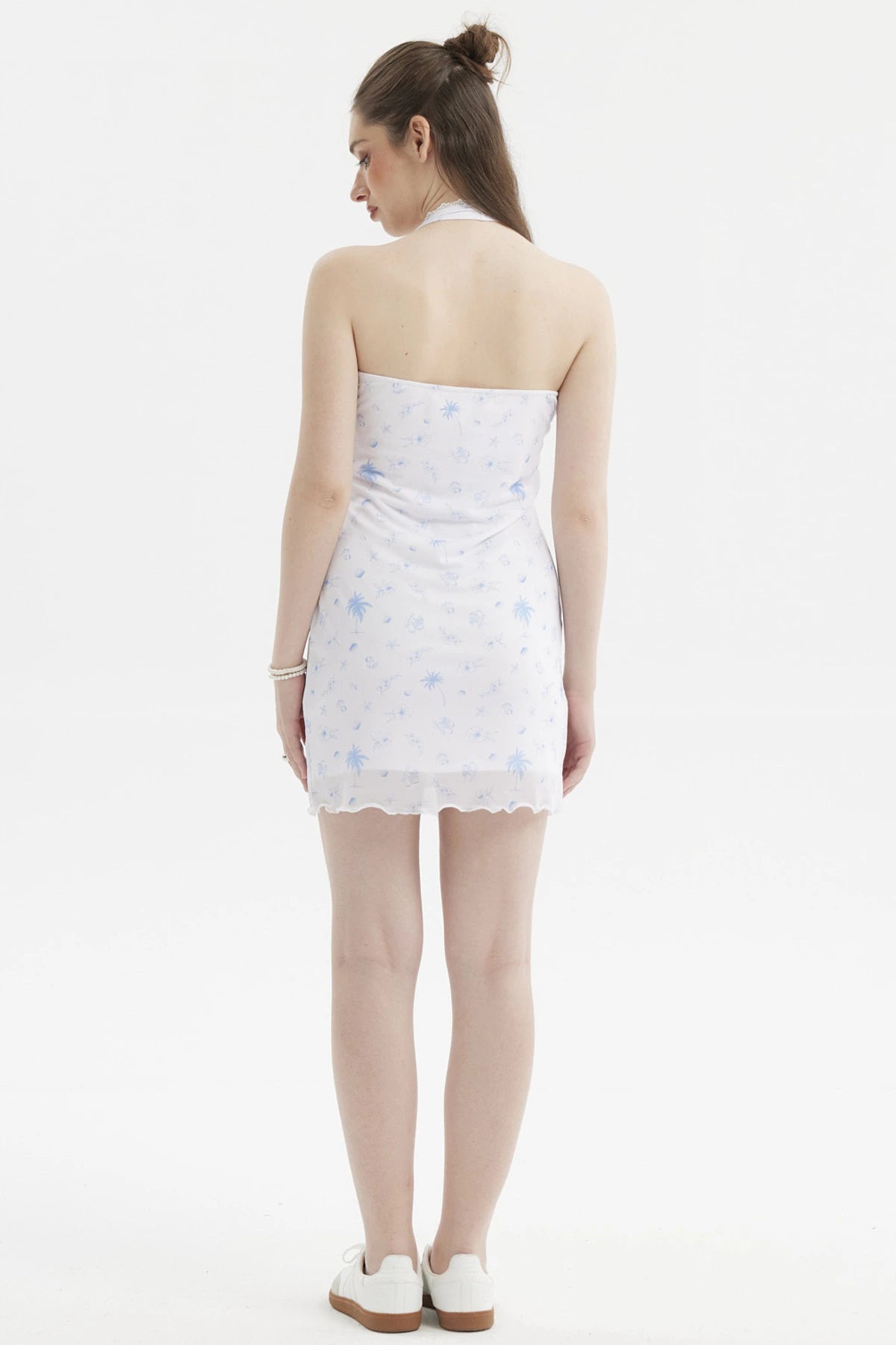Vestido corto blanco con estampado azul de palmeras y flores pequeñas en estilo tropical a lo largo del vestido