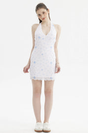 Vestido corto blanco con estampado azul de palmeras y flores pequeñas en estilo tropical a lo largo del vestido