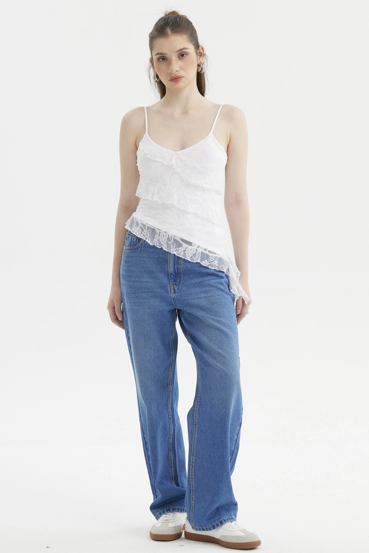 Peto blanco con basta asimétrica y encaje floral sobre fondo liso estilo casual