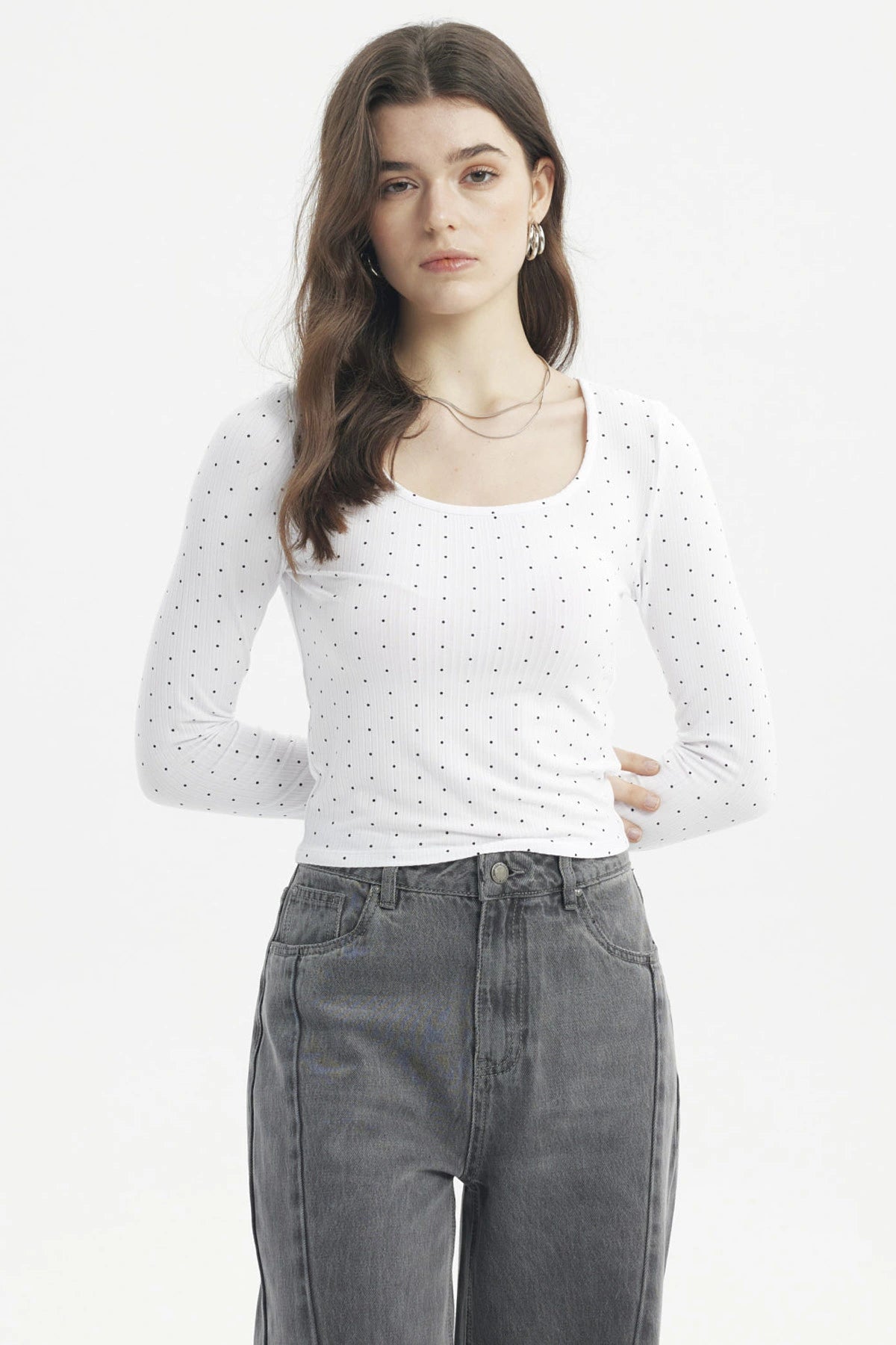 Polera blanca de mujer con cuello redondo y estampado de pequeños puntos negros lisa ajustada y de manga larga