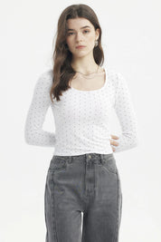 Polera blanca de mujer con cuello redondo y estampado de pequeños puntos negros lisa ajustada y de manga larga