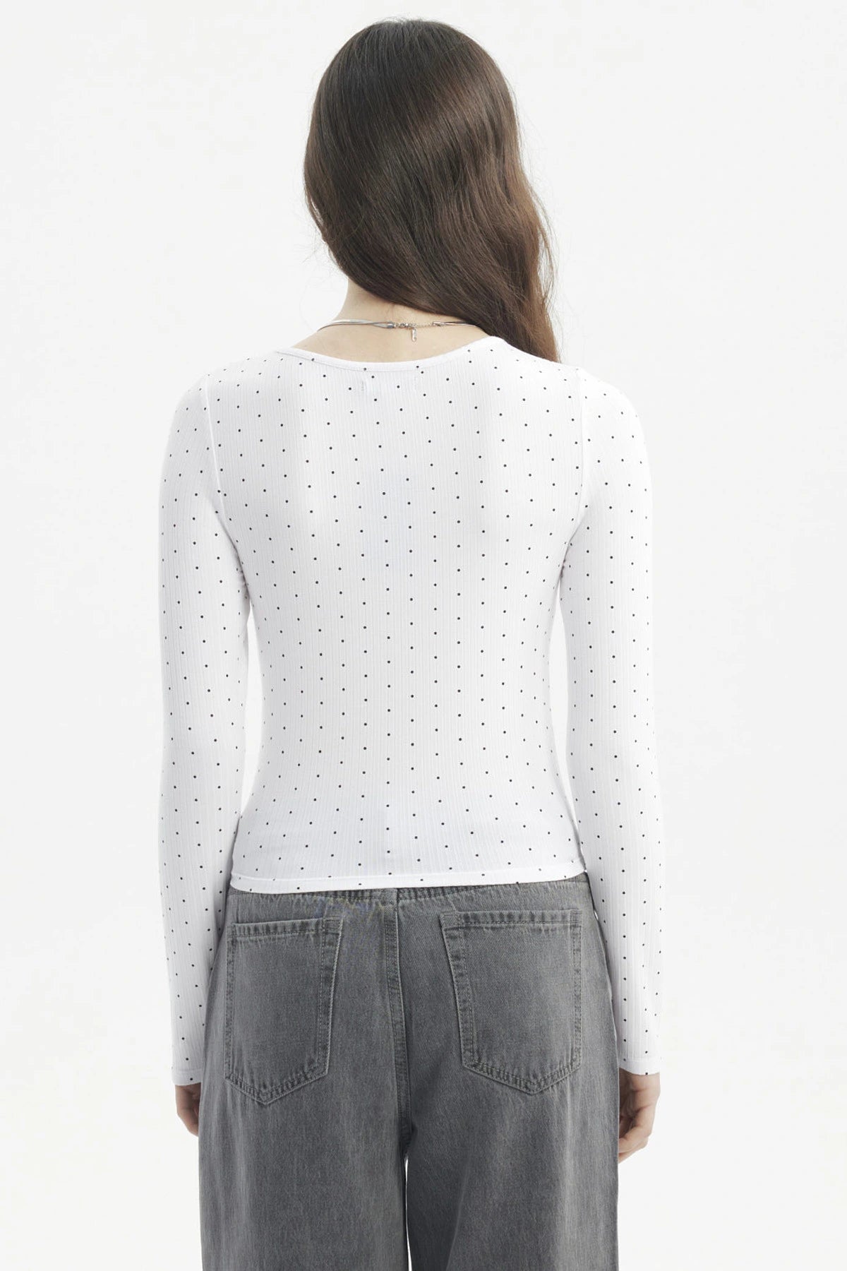 Polera blanca de mujer con cuello redondo y estampado de pequeños puntos negros lisa ajustada y de manga larga