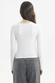 Polera blanca de mujer con cuello redondo y estampado de pequeños puntos negros lisa ajustada y de manga larga