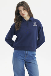 Polerón mujer slim azul con cuello polo y botones delanteros diseño escudo y texto blanco en el pecho estilo casual