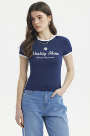 Polera ajustada azul con borde blanco y texto frontal Vitality Shine Vibrant Movement estilo casual moderno