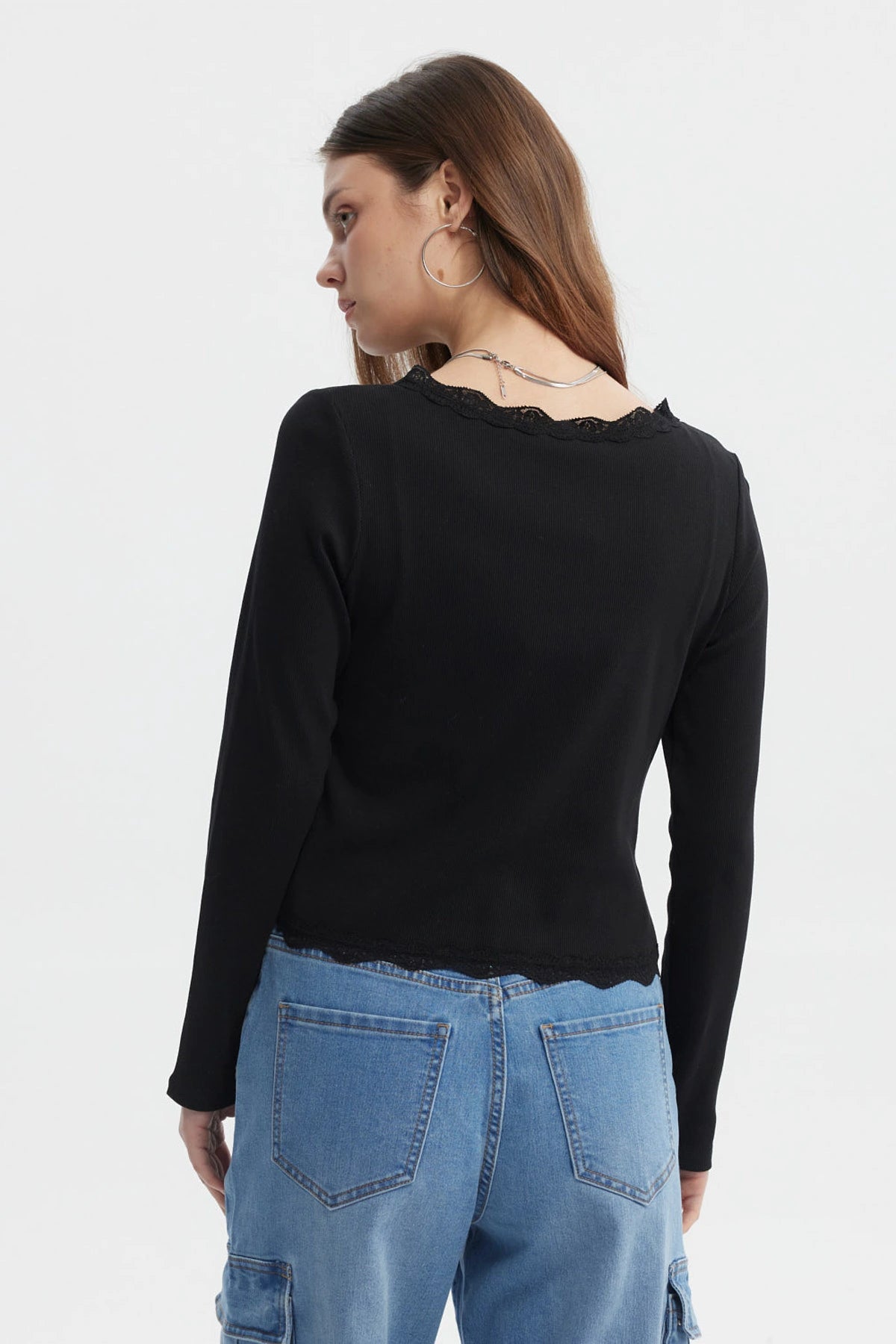 Polera negra de mujer con cuello en V y encaje en puños prenda lisa con botones en el frente
