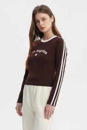 Polera de mujer café oscuro con texto Los Angeles y estrella blanca en el pecho manga larga y franjas blancas en las mangas