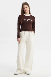 Polera de mujer café oscuro con texto Los Angeles y estrella blanca en el pecho manga larga y franjas blancas en las mangas
