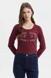 Polera roja de mujer con cuello redondo y botones decorativos frontal texto West Wish 1968 Good Luck estilo casual