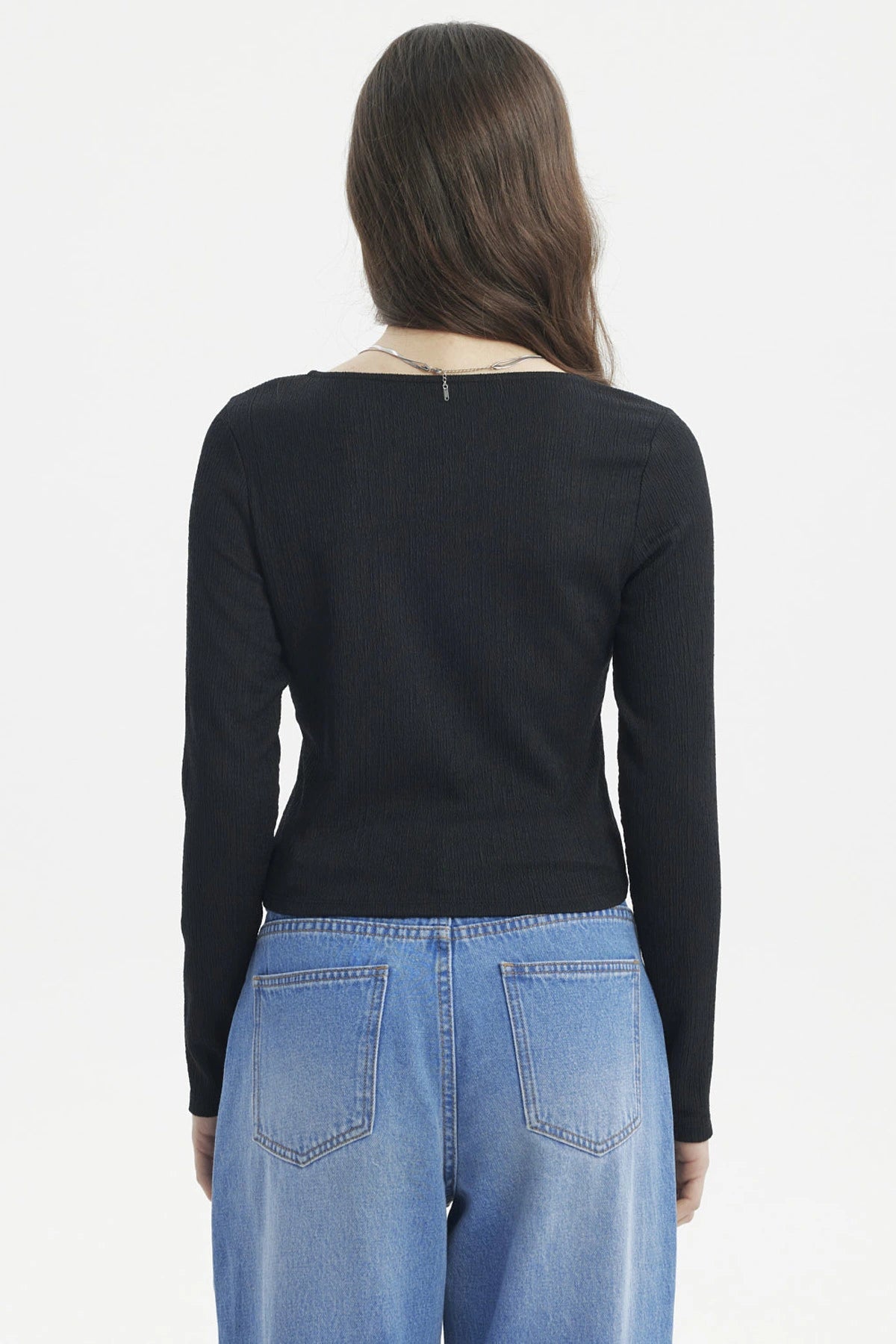 Polera negra de mujer con cuello asimétrico y manga larga lisa