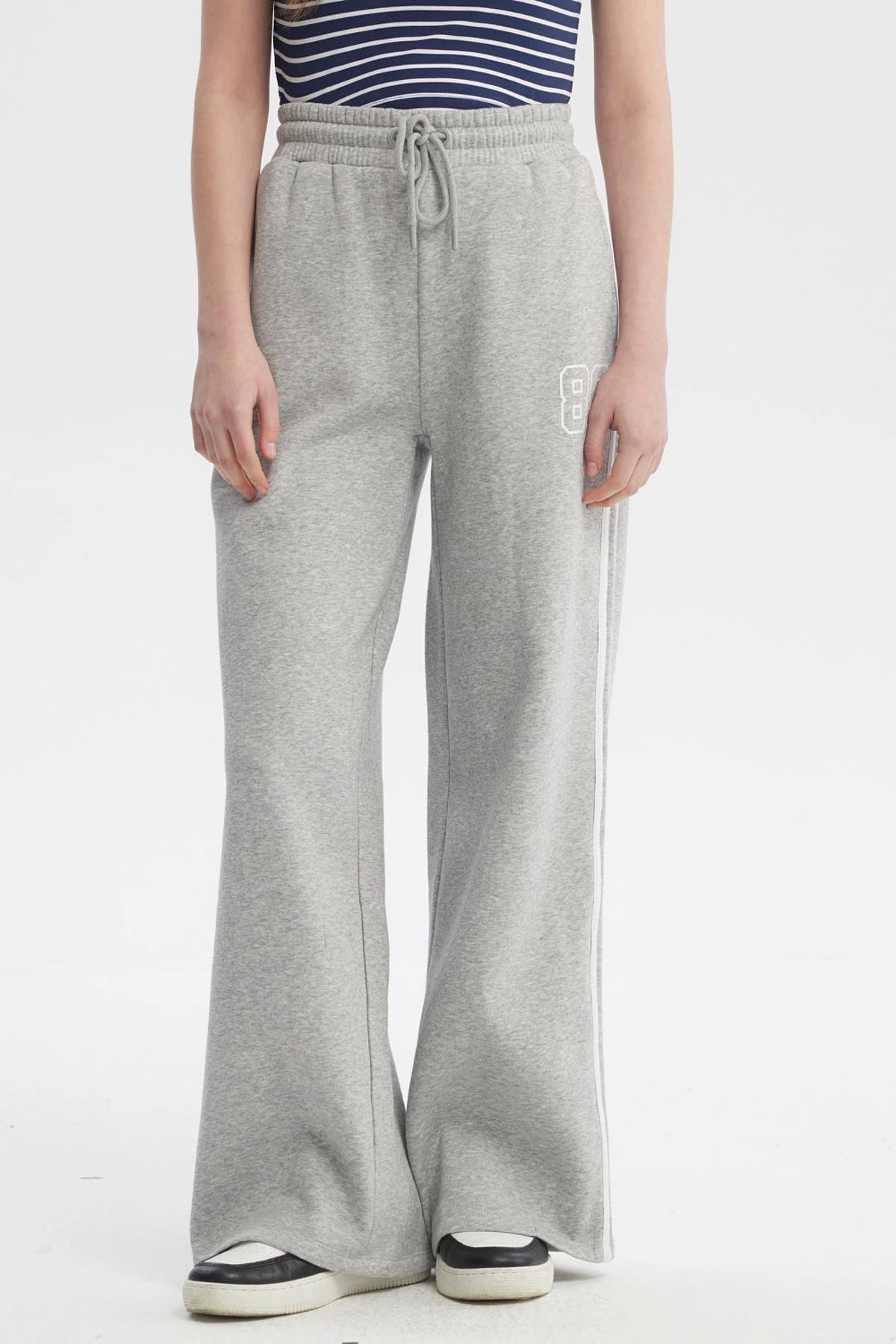 Pantalón buzo gris melange para mujer con cintas blancas a los costados diseño número 89 pequeño en el muslo izquierdo