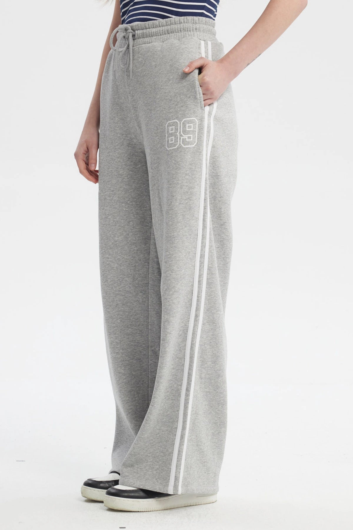 Pantalón buzo gris melange para mujer con cintas blancas a los costados diseño número 89 pequeño en el muslo izquierdo