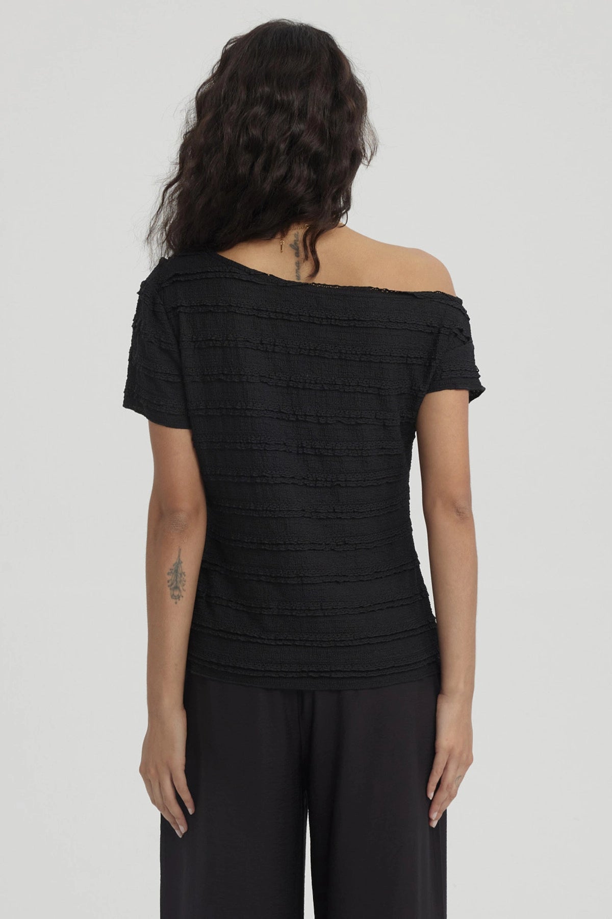 Polera negra para mujer con cuello asimétrico textura de líneas horizontales diseño liso y elegante