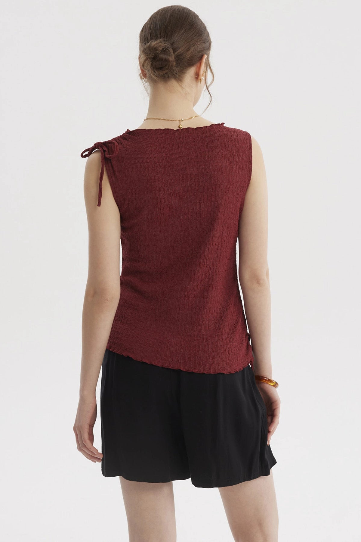 Polera sin mangas color vino con textura arrugada y amarre en el hombro derecho lisa y casual