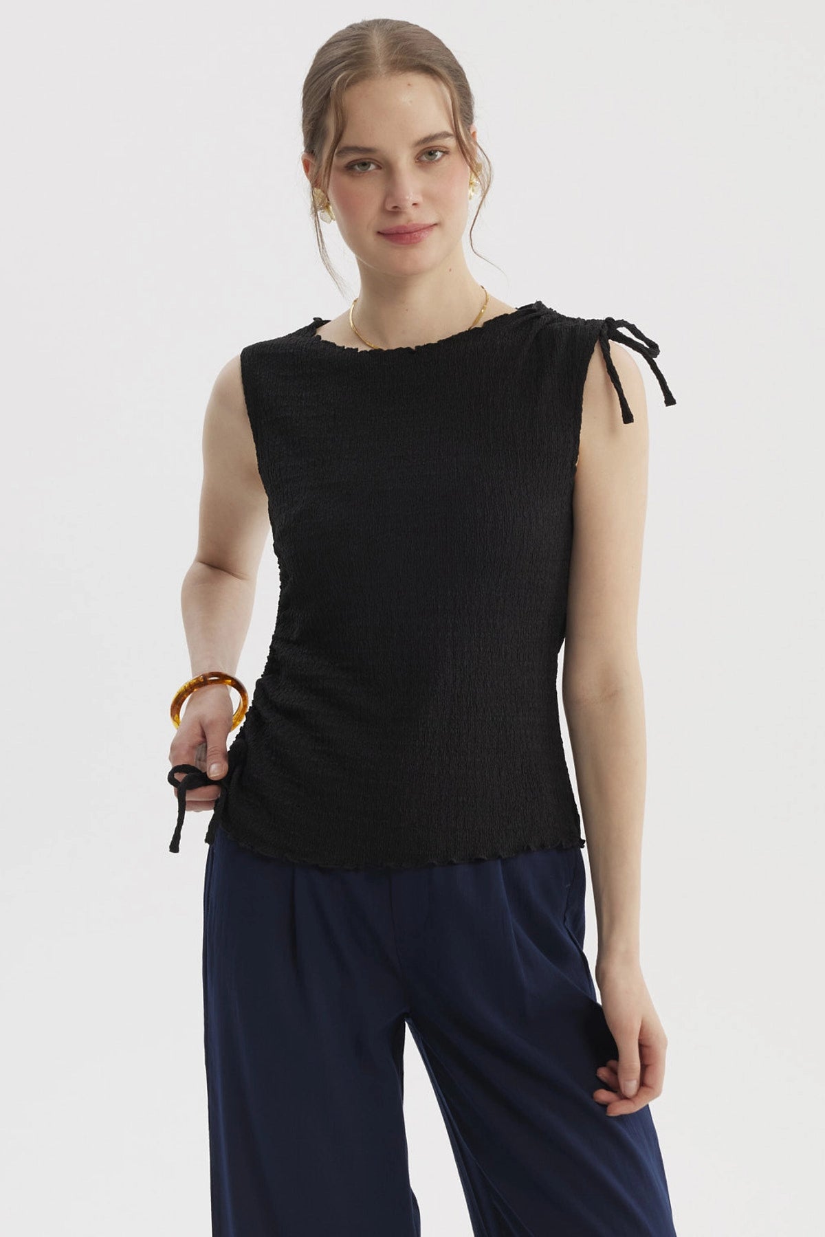 Polera negra sin mangas con detalle de amarre en el costado diseño liso ideal para un look elegante y casual