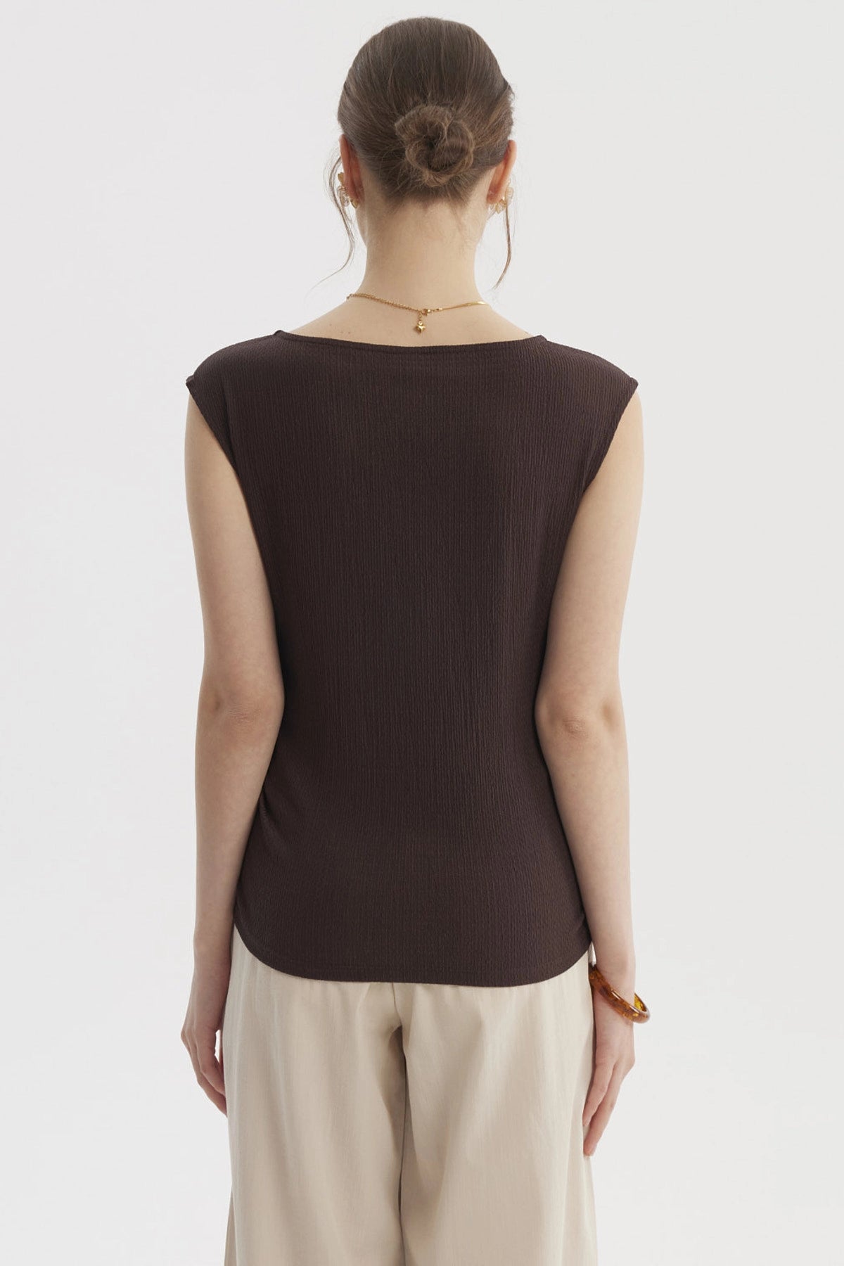 Polera de mujer color café oscuro con diseño drapeado y textura lisa sin estampas