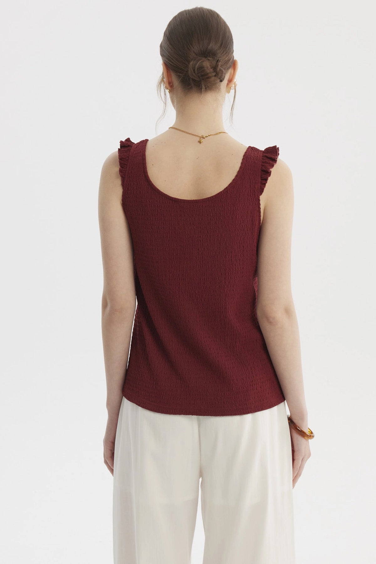 Polera sin mangas color vino con botones dorados y detalles de vuelo en los hombros lisa elegante y moderna
