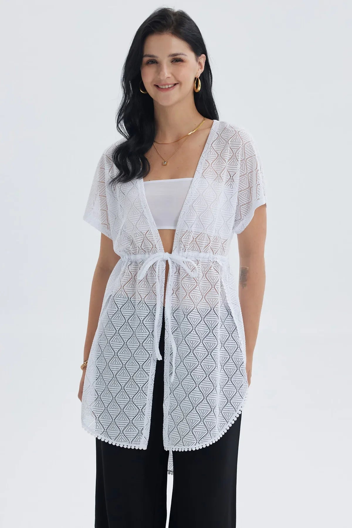 Polera blanca de encaje con diseño geométrico y lazo en la cintura