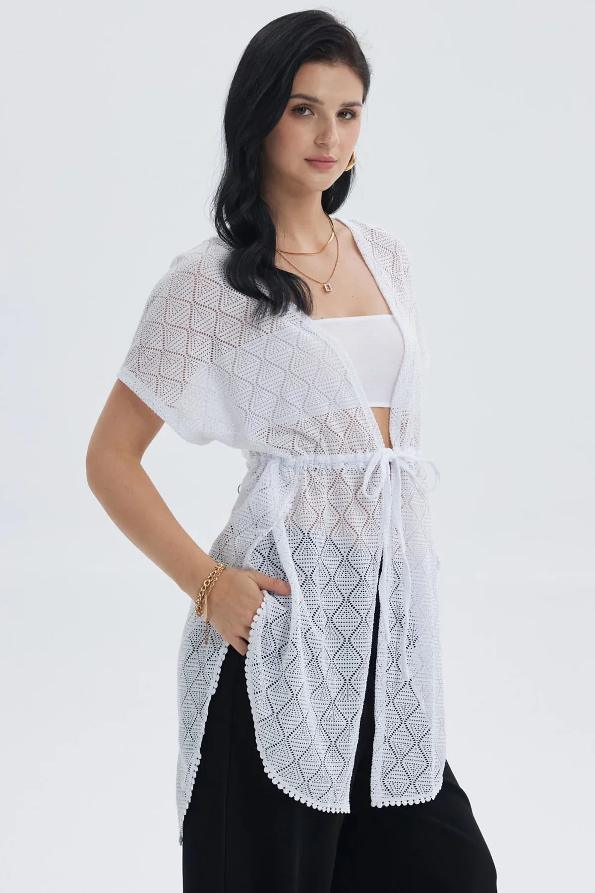 Polera blanca de encaje con diseño geométrico y lazo en la cintura