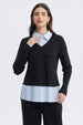 Sweater casual negro de mujer con cuello en V sobre camisa azul con rayas blancas visible en el borde inferior