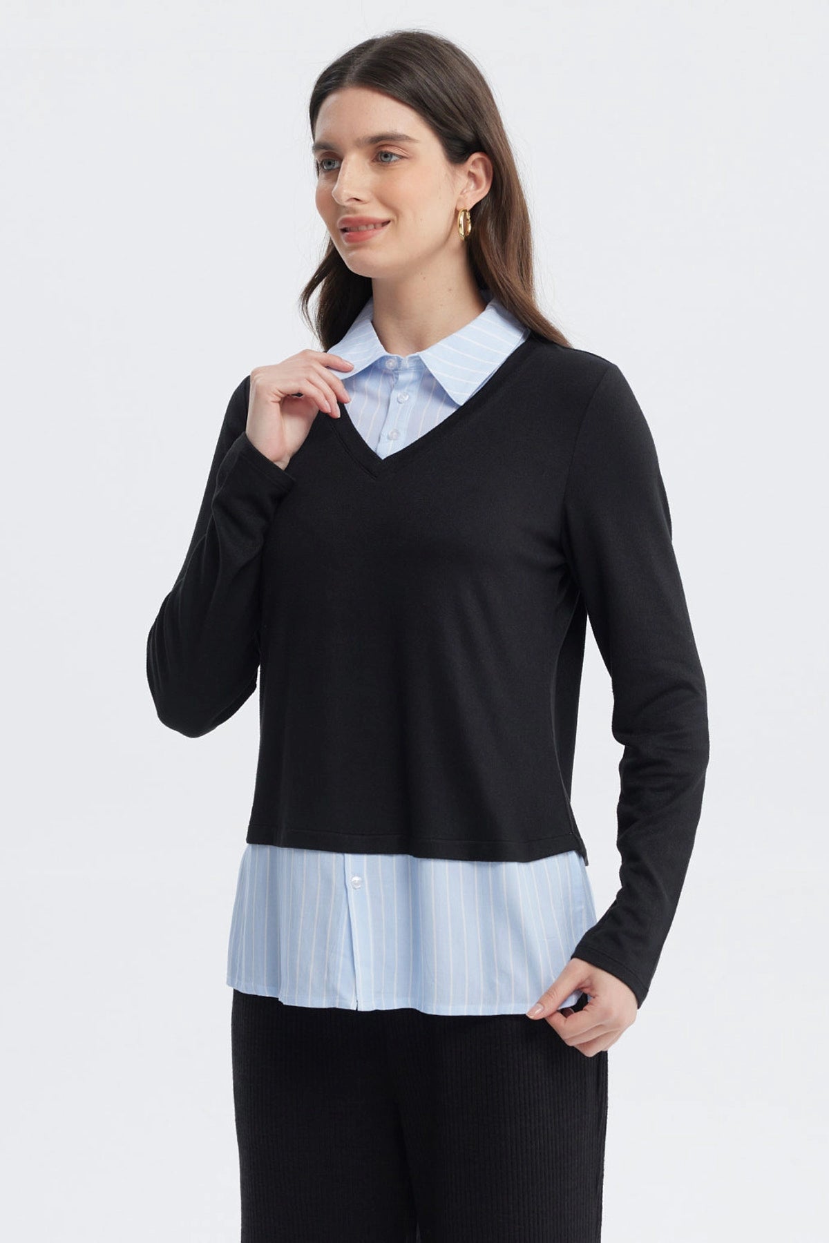 Sweater casual negro de mujer con cuello en V sobre camisa azul con rayas blancas visible en el borde inferior