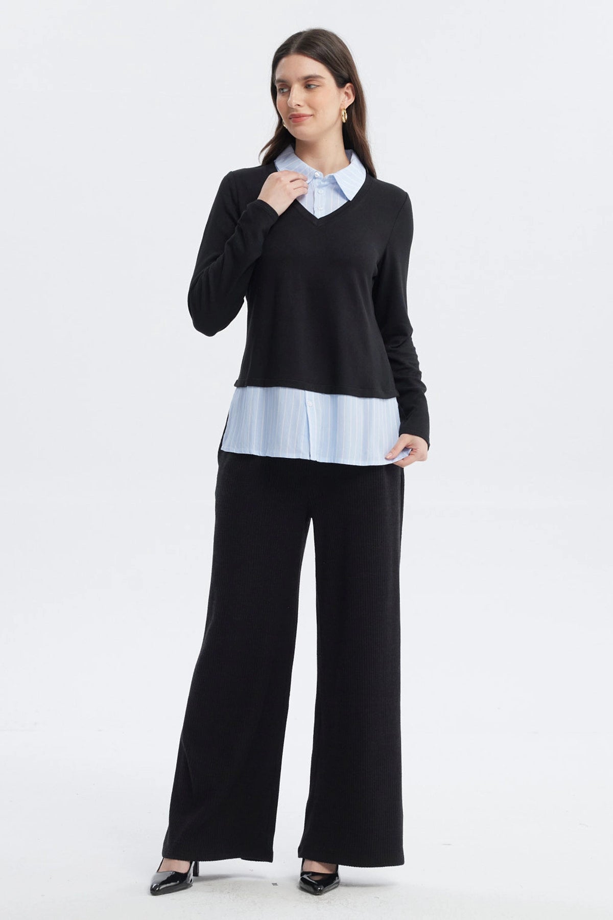 Sweater casual negro de mujer con cuello en V sobre camisa azul con rayas blancas visible en el borde inferior