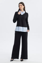 Sweater casual negro de mujer con cuello en V sobre camisa azul con rayas blancas visible en el borde inferior