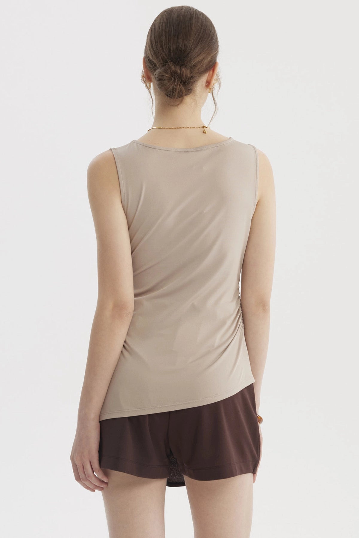 Polera mujer beige claro sin mangas con basta asimétrica diseño liso ajuste en la cintura ideal para un look casual elegante