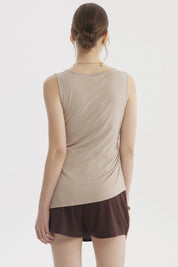 Polera mujer beige claro sin mangas con basta asimétrica diseño liso ajuste en la cintura ideal para un look casual elegante