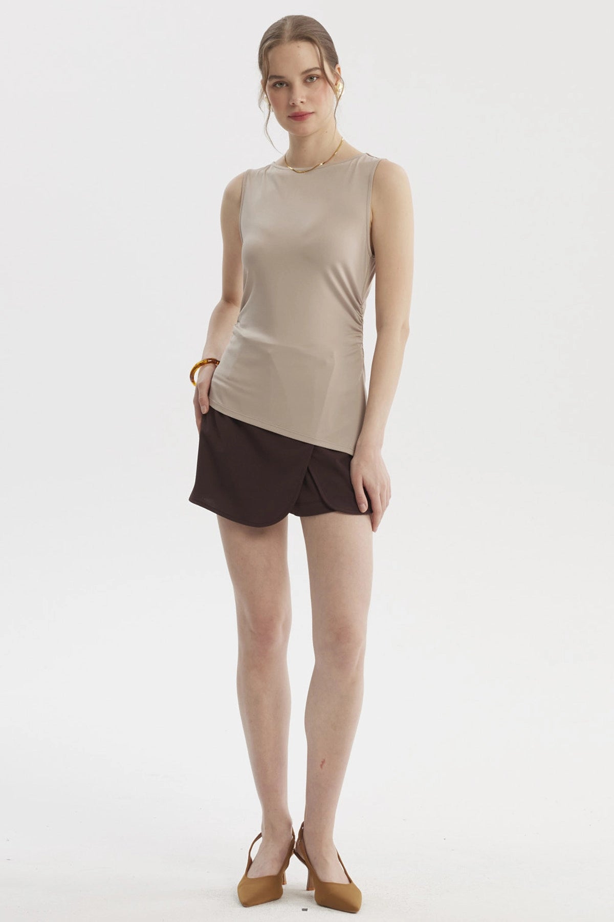 Polera mujer beige claro sin mangas con basta asimétrica diseño liso ajuste en la cintura ideal para un look casual elegante