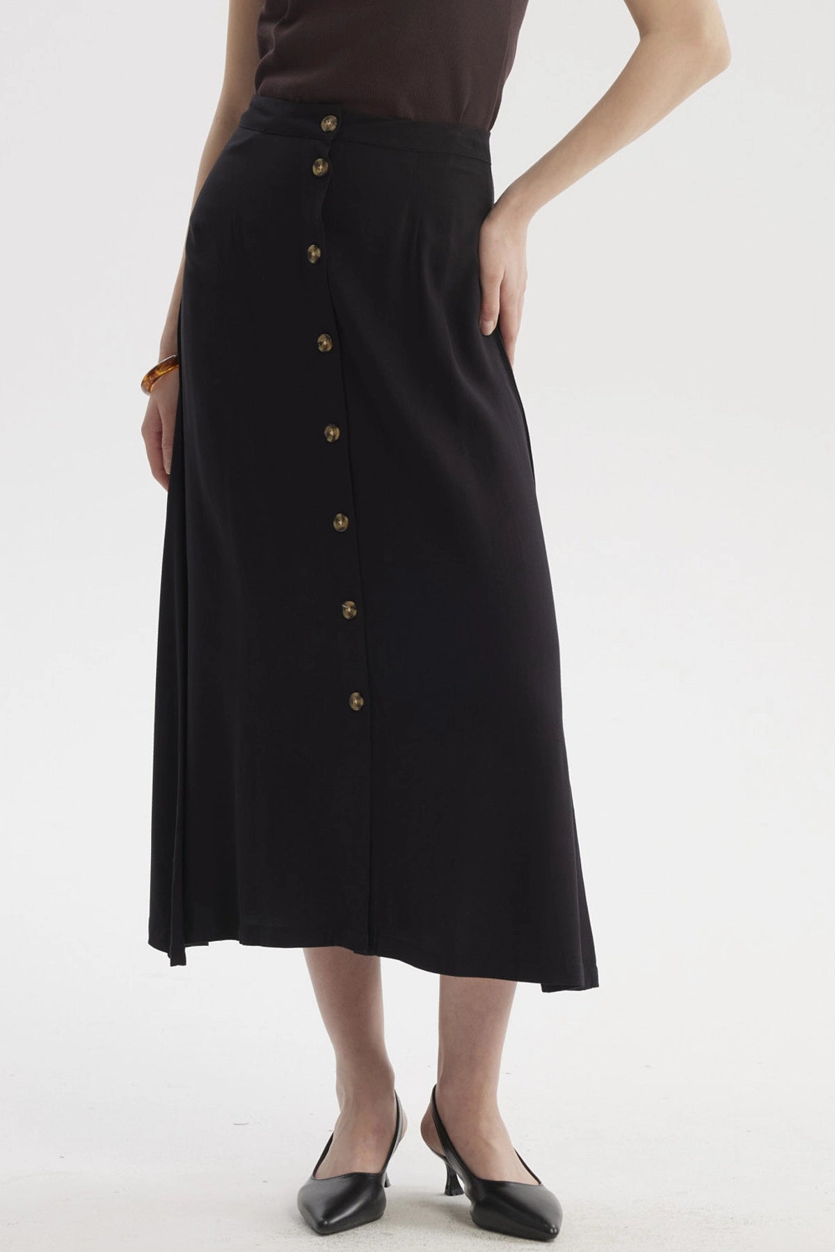 Falda midi negra con botones frontales dorados prenda lisa elegante para un look casual y sofisticado