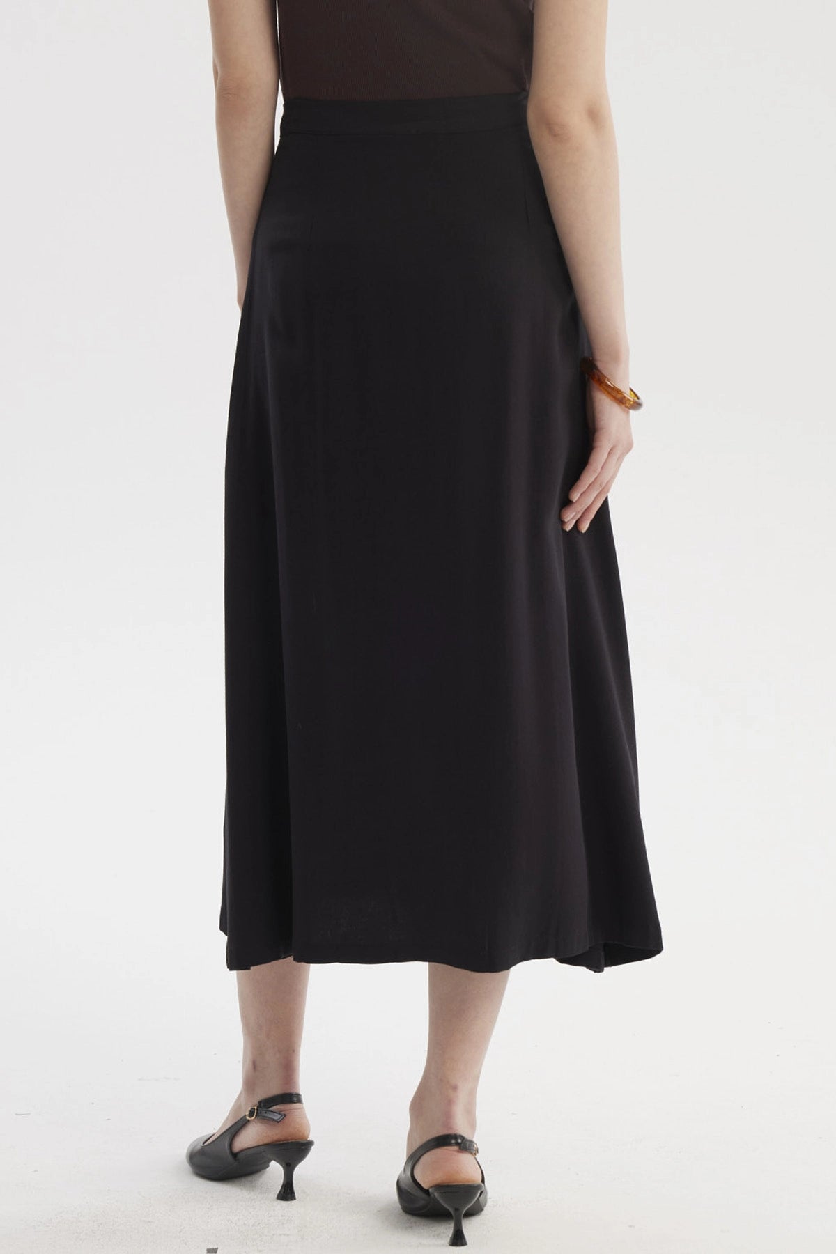 Falda midi negra con botones frontales dorados prenda lisa elegante para un look casual y sofisticado