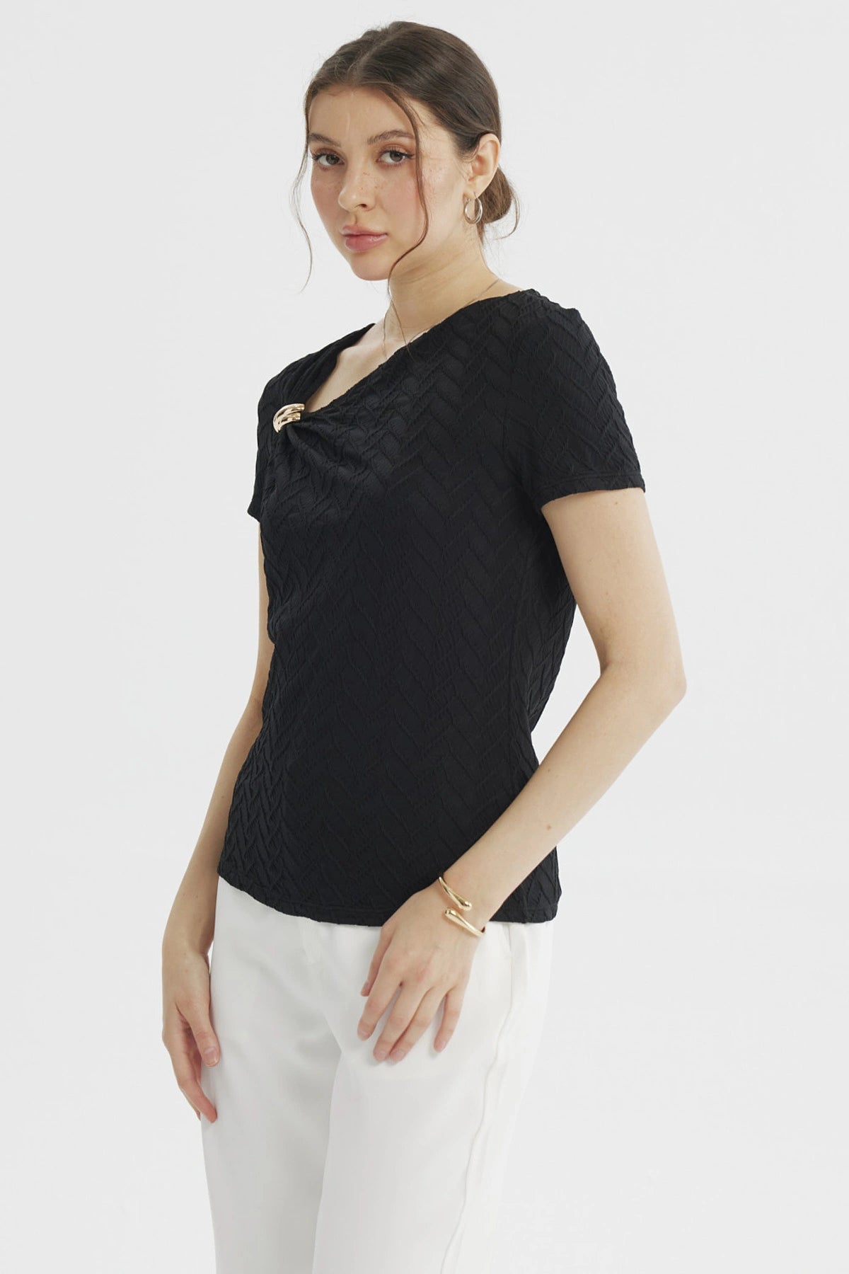 Polera negra de mujer con cuello asimétrico y detalle dorado en el hombro textura en patrón de chevron lisa