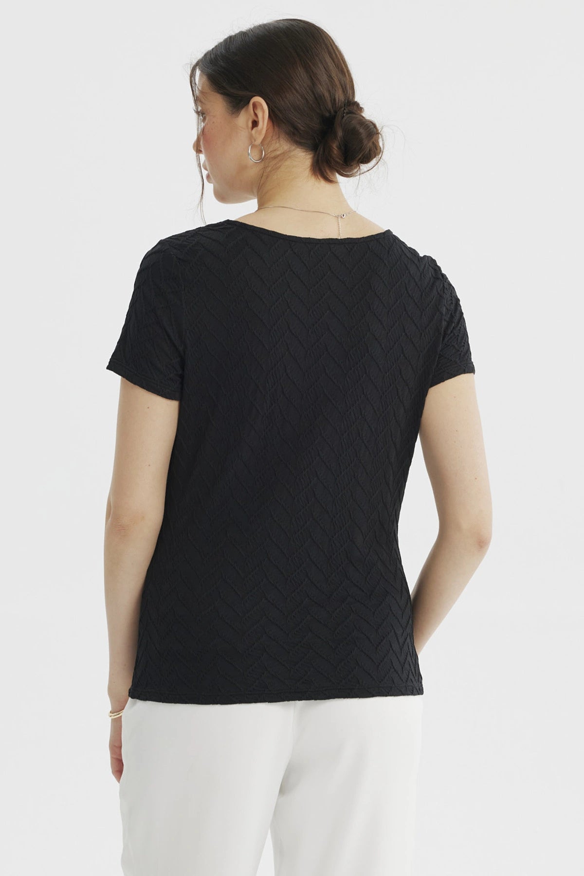 Polera negra de mujer con cuello asimétrico y detalle dorado en el hombro textura en patrón de chevron lisa