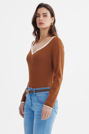 Polera ajustada café con cuello V y ribete blanco sin estampado visible elegante y moderna