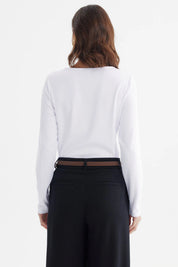 Polera ajustada blanca de manga larga con detalle de abertura y broche dorado en el escote sin estampa lisa