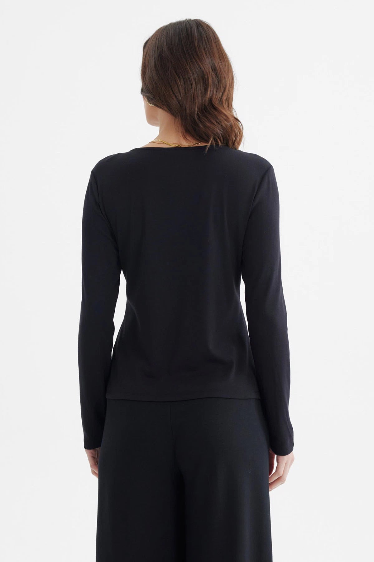 Polera negra de mujer con manga larga abertura en el hombro derecho y nudo estilizado diseño liso elegante